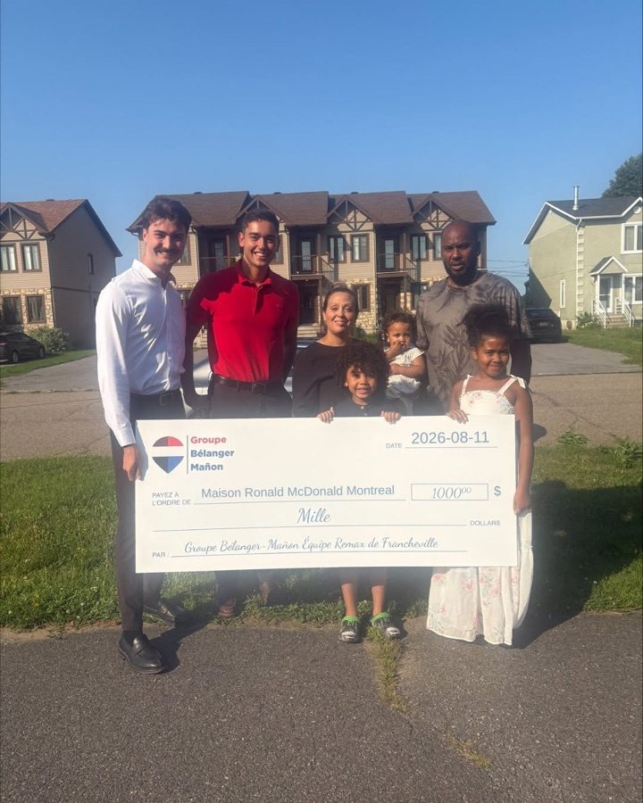 Remise d'un chèque de 1 000 $ à une famille devant des maisons de ville